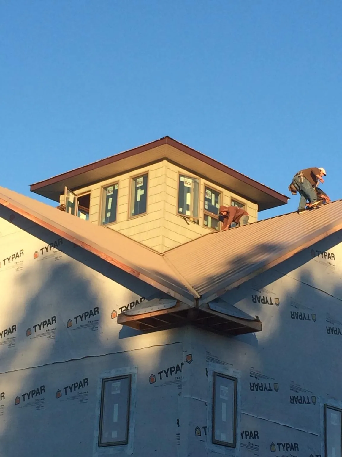 Roofers working around a rooftop cupola on a new metal roof at sunset — Roof Waterproofing in Middleton by Roofing Brothers